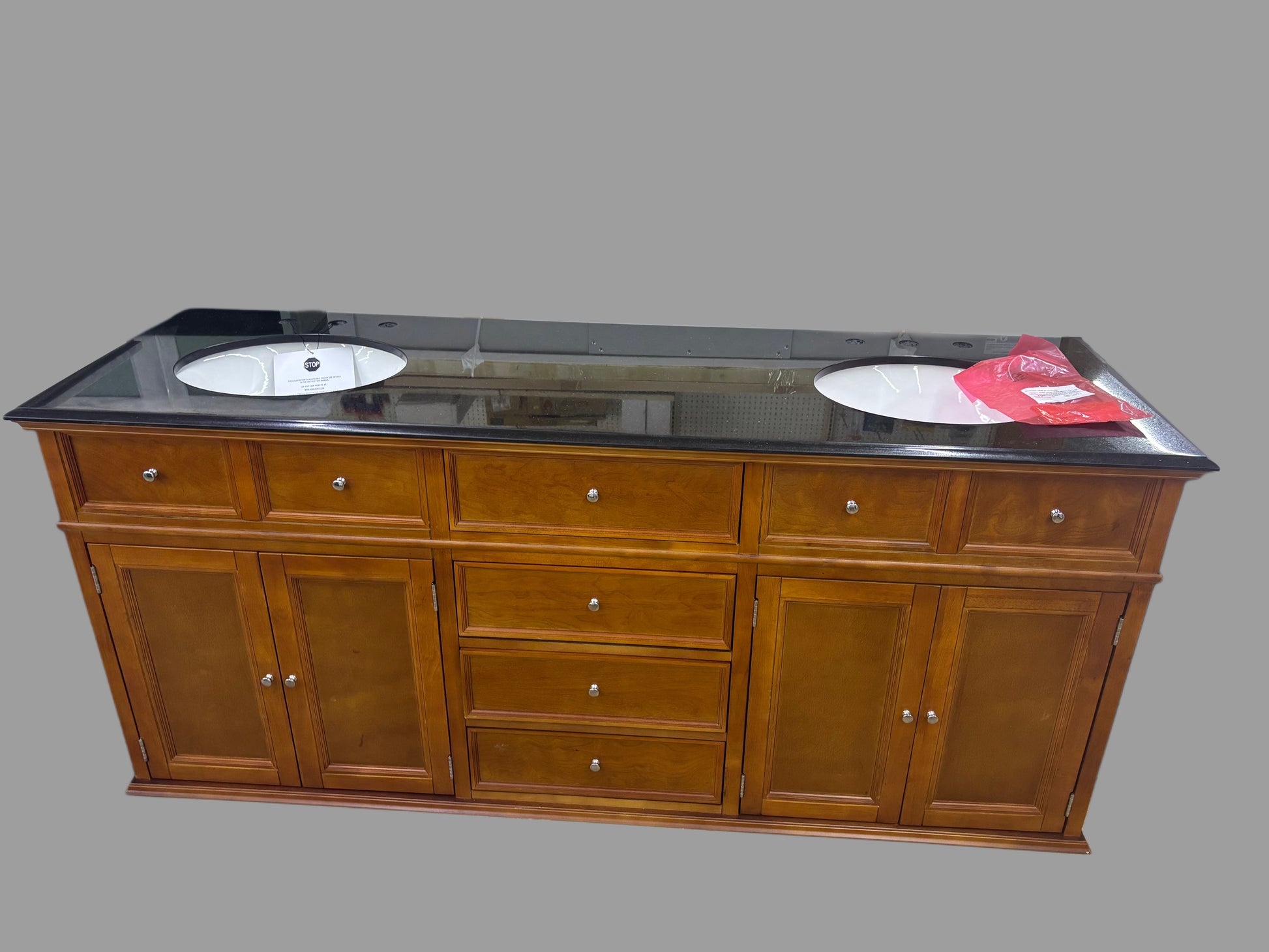 Wooden bathroom vanity with black countertop on a gray background